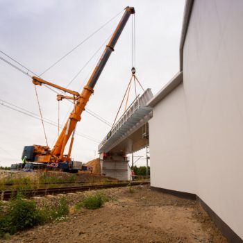 Zdjęcie: pomarańczowy dźwig podnosi przęsło wiaduktu w Toszku.