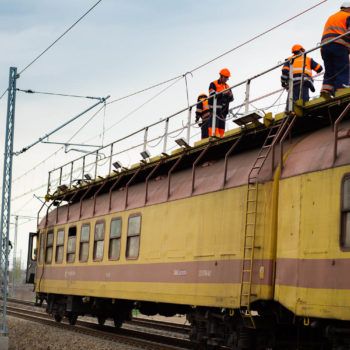 Zdjęcie: pociąg do podwieszania trakcji z robotnikami pracującymi na górze.