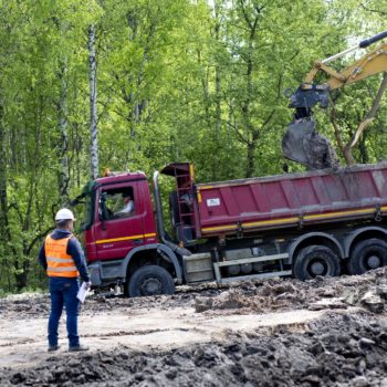 Zdjęcie: Koparka nagarnia ziemie z nasypu w Trzebini. Na pierwszym planie kierownik obserwuje prace.