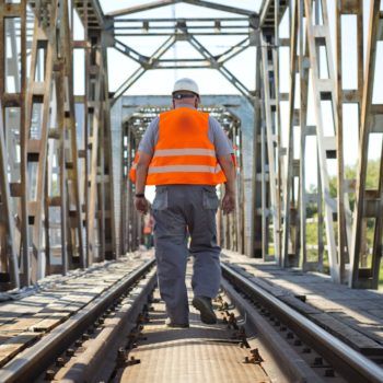 Zdjęcie: robotnik w pomarańczowej kamizelce idzie wzdłuż mostu na Wiśle.