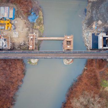 Zdjęcie: symetryczny kadr z powietrza na miejsce ustawienia końcowego mostu na rzece Białej.