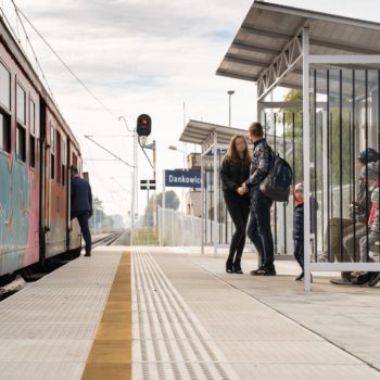 Zdjęcie: pasażerowie stoją obok pociągu.