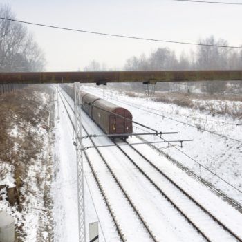 Zdjęcie: w zimowym otoczeniu przejeżdża pociąg towarowy.