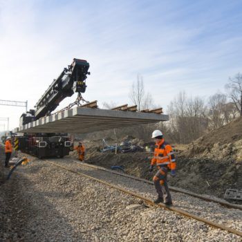 Zdjęcie: widok na pracujący dźwig kolejowy który transportuje podkłady.