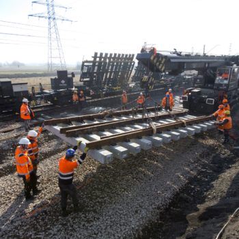 Zdjęcie: widok na pracujący dźwig kolejowy który transportuje podkłady.