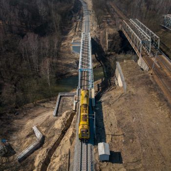 Zdjęcie: żółta lokomotywa przejeżdża przez wiadukt.